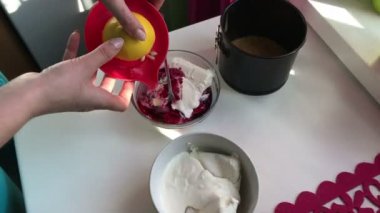 Kadın için süzme peynir limon suyu ekler. Yaban mersinli cheesecake. Yemek pişirmek için malzemeler tablo yüzeyinde yer alır.