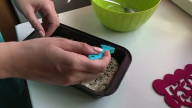 Evde ekmek. Kepekli hamur ekmek tavada yatıyor. Bir kadın ile ayçiçeği tohumu hamur sprinkles.