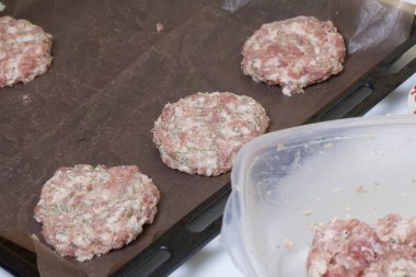 Kıyılmış et pirzola fırın tepsisine vardır. Kıyma biftek patates, yumurta ve peynir ile. Pişirme adımları ve malzemeler.