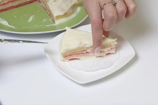 Cocinar el pastel con crema de mascarpone. El pastel terminado, untado con impregnación, yace en el plato. Una mujer le corta un pedazo. Un pedazo de ella está cortada . — Foto de Stock