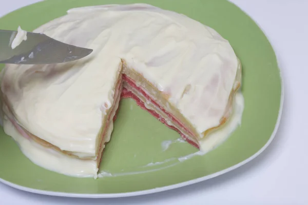 Cucinare la torta con crema di mascarpone. La torta finita, imbrattata di impregnazione, giace sul piatto. I livelli di colore sono visibili . — Foto Stock