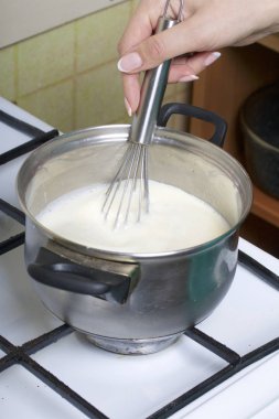 Süt jöle yemek. Pasta Bisküvi kırıntıları ve süt jöle yemek. Tablo yüzeyinde malzemeler ve mutfak aletleri vardır.