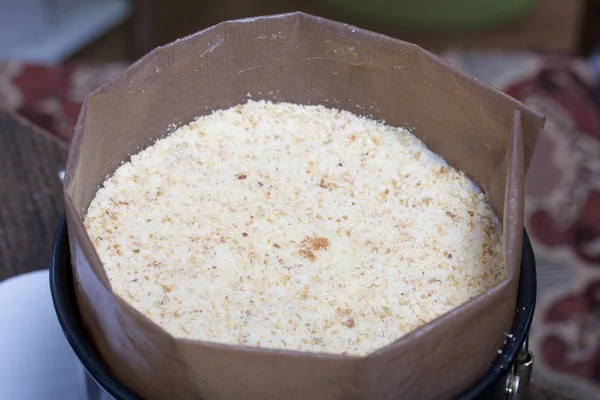 Matlagning en tårta av kex smulor och mjölken gelé. På ytan av tabellen är ingredienser och köksredskap. — Stockfoto