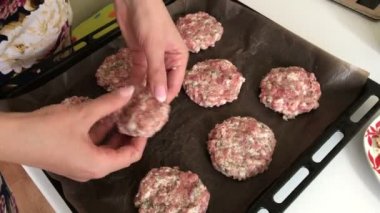 Bir kadın kıyma köftesi sculpts ve onları fırın tepsisine bırakır. Kıyma biftek patates, yumurta ve peynir ile. Pişirme adımları ve malzemeler.