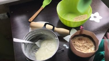 Kadın pandispanya kek kalıp için ekler. Pasta Bisküvi kırıntıları ve süt jöle yemek. Tablo yüzeyinde malzemeler ve mutfak aletleri vardır.