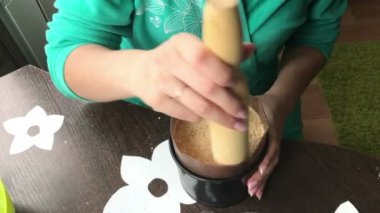 Kadın pandispanya kek kalıp için ekler. Ahşap bir oklava ile katman mühürler. Yemek kek bisküvi kırıntıları ve süt jöle.