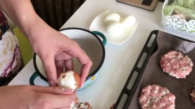 Kadın haşlanmış tavuk yumurtası temizler. Kıyma biftek patates, yumurta ve peynir ile. Pişirme adımları ve malzemeler.