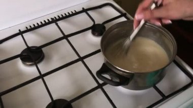 Kadın aşçılar muhallebi. Pasta Bisküvi kırıntıları ve süt jöle yemek. Tablo yüzeyinde malzemeler ve mutfak aletleri vardır.