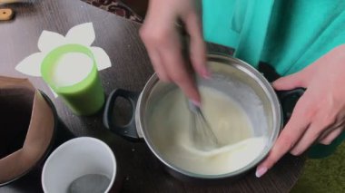 Kadın aşçılar muhallebi. Pasta Bisküvi kırıntıları ve süt jöle yemek. Tablo yüzeyinde malzemeler ve mutfak aletleri vardır.