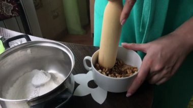 Kadın polisler ceviz. Pasta Bisküvi kırıntıları ve süt jöle yemek. Tablo yüzeyinde malzemeler ve mutfak aletleri vardır.