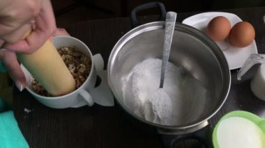 Kadın polisler ceviz. Pasta Bisküvi kırıntıları ve süt jöle yemek. Tablo yüzeyinde malzemeler ve mutfak aletleri vardır.