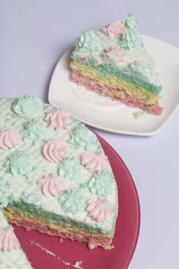 Parça kesilir ve bir daire üzerinde yan yana yatıyor. Krem yapılan gözleme pasta kek batırılmış. Krem çiçeklerle süslenmiş.