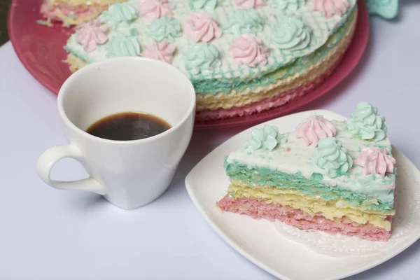 La pieza se corta y se acuesta lado a lado en un platillo. Cerca hay una taza de café. Pastel de gofres hecho de pasteles empapados en crema. Decorado con flores de crema . — Foto de Stock