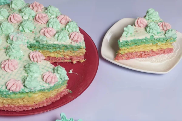 Kawałek jest odcięte i znajduje się obok siebie na spodek. Wafel ciasto z kremem nasączone ciasta. Ozdobiona kremowymi kwiatkami. — Zdjęcie stockowe