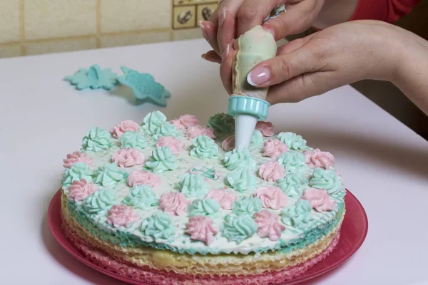 一个女人用糕点袋里的奶油装饰蛋糕。用奶油浸渍蛋糕制成的华夫蛋糕。用奶油花装饰. — 图库照片
