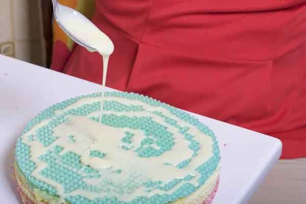 Una mujer lubrica los pasteles y los pone en una pila. Tortas redondas de obleas de diferentes colores. Por hacer tarta de gofres. Cerca hay una lata de leche condensada para remojar los pasteles . — Foto de Stock