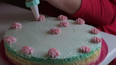 Kadın waffle pasta süsle. Krem çiçek yapar. Hamur işi çanta yardımı ile.