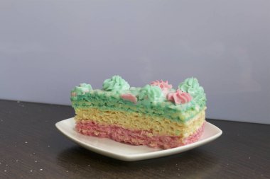 Parça kesilir ve bir daire üzerinde yan yana yatıyor. Krem yapılan gözleme pasta kek batırılmış. Krem çiçeklerle süslenmiş.