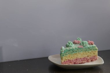 Parça kesilir ve bir daire üzerinde yan yana yatıyor. Krem yapılan gözleme pasta kek batırılmış. Krem çiçeklerle süslenmiş.