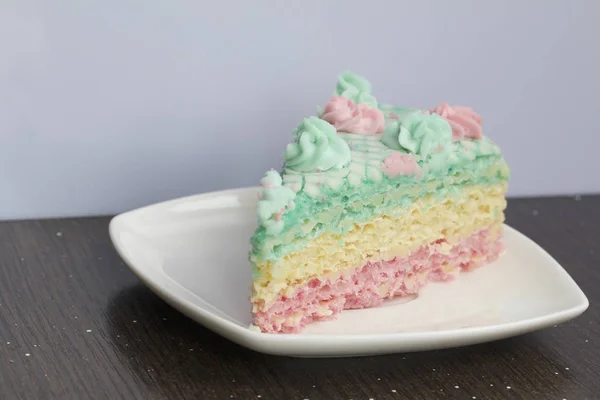 Das Stück wird abgeschnitten und liegt nebeneinander auf einer Untertasse. Waffelkuchen aus cremegetränkten Kuchen. dekoriert mit cremefarbenen Blüten. — Stockfoto