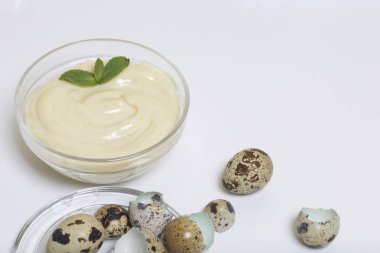 El yapımı mayonez bıldırcın yumurtası kullanarak. Bir cam kap içinde yeşillik ile dekore edilmiştir. Bıldırcın yumurtası ve kabuk onlardan yakın. Beyaz bir arka plan üzerinde.