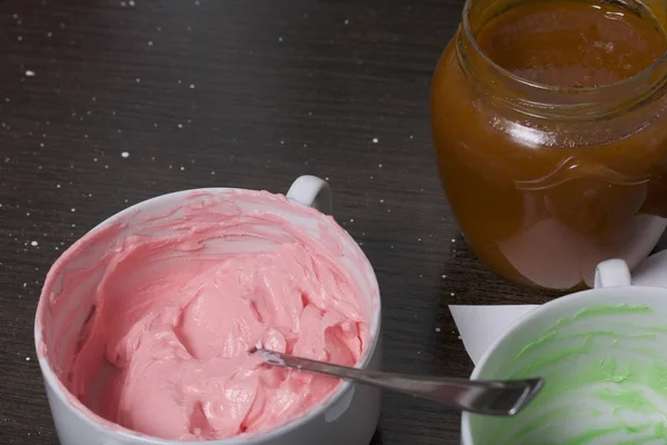 Crème de différentes couleurs pour décorer le panier de gâteau. A proximité se trouve un pot de confiture . — Photo