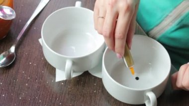Bir kadın gıda renklerini farklı bir fincan için ekler. Renkli krem hazırlanması için