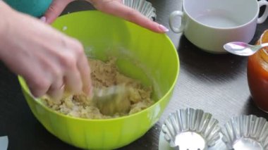 Kadın kek yemek pişirmek için hamur kneads. Kek ve diğer maddeler pişirme için formları masaya standı.