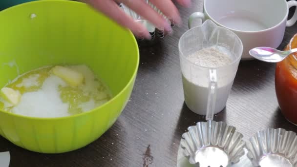 여자는 버터의 컨테이너에 밀가루와 설탕을 추가합니다 케이크 반죽을 — 비디오