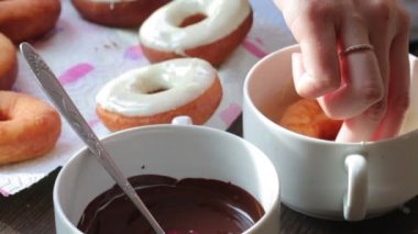 Bir kadın eritilmiş çikolata ayçiçeği yağda kızartılmış Amerikan donut dips.