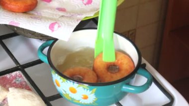 Bir kadın Amerikan donut yemek pişiriyor. Onları ayçiçek yağı fırında. Yakın donuts pişer.