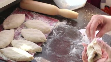 Bir kadın pasties hazırlar. Doldurma hamur içinde sarın. Masaya boşlukları pasties vardır.