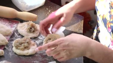 Bir kadın pasties hazırlar. Doldurma hamur içinde sarın. Masaya boşlukları pasties vardır.