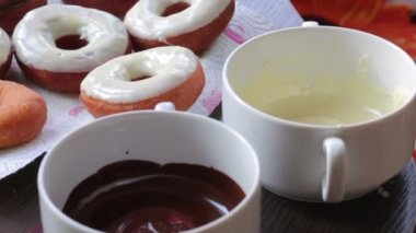 Amerikan donut, eritilmiş çikolata ile sırlı bir tepside yalan. Yanındaki kapsayıcılar eritilmiş çikolata.