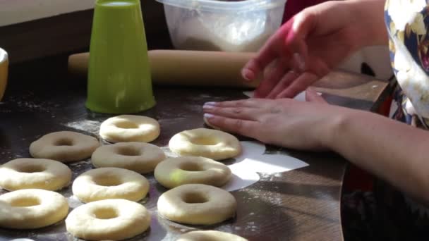 女性は アメリカのドーナツのブランクを作る 生地で作られた テーブルの表面上にあります 近くには調理用ツールです — ストック動画