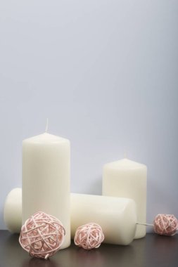 Beyaz renkte dokuma doğal malzemelerden dekoratif topları arasında mumlar.