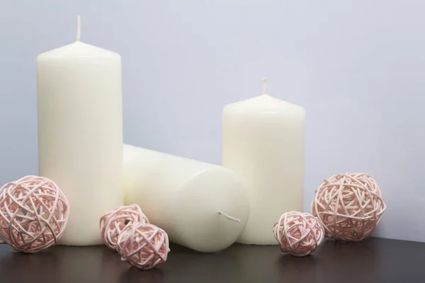 Svíčky bílé barvy mezi dekorační koule, tkané z přírodních materiálů. — Stock fotografie