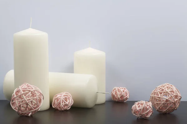 Velas de cor branca entre as bolas decorativas, tecidas de materiais naturais . — Fotografia de Stock