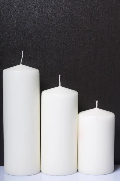 Candles white in different sizes. White background turning into dark. — Stock Photo, Image
