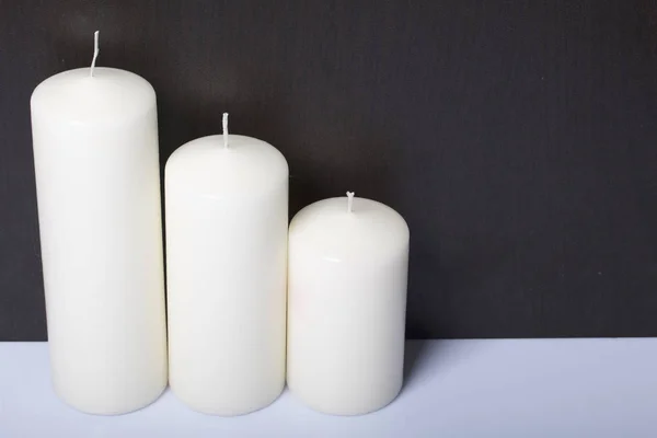 Świeczki biały w różnych rozmiarach. Białe tło, zamieniając w ciemności. — Zdjęcie stockowe