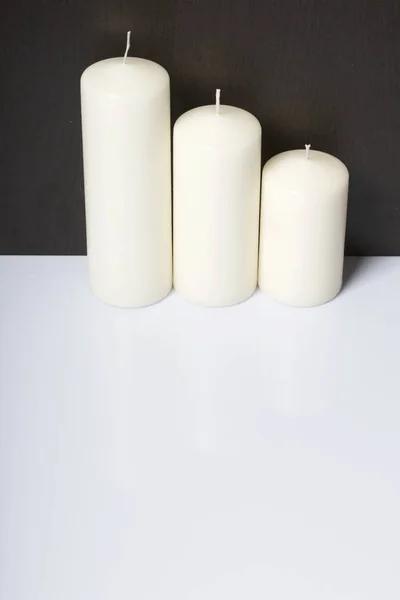 Velas brancas em tamanhos diferentes. Fundo branco transformando-se em escuro . — Fotografia de Stock