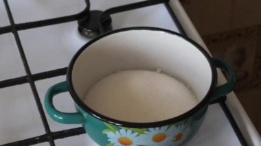 Bir kadın bir kabın içine şeker dökülen ve suda seyreltilmiş agar yalıyor. Hatmi yapmak için.