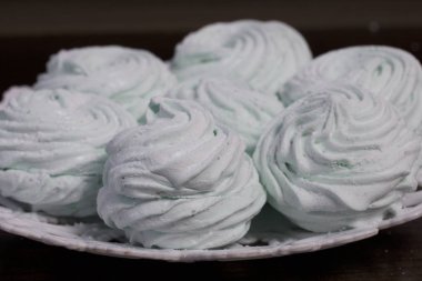 Ev yapımı krema bir tabağa koydu. Marshmallow ile nane, yeşil bir renk tonu ile. Karanlık bir arka plan üzerinde.