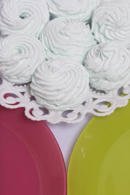 Ev yapımı krema bir tabağa koydu. Marshmallow ile nane, yeşil bir renk tonu ile. Yakınlarda pembe ve hafif yeşil plakaları bulunmaktadır.