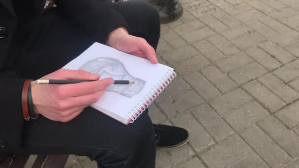 Jeune Homme Assoit Sur Banc Fait Des Croquis Dans Carnet — Video