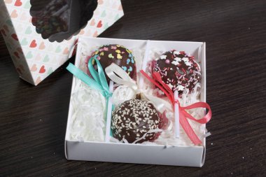 Pasta çıkar güzel bir hediye kutusunda paketlenmiştir. Yakınlarda bir saydam pencere ile bir kapak var. Karanlık bir arka plan üzerinde.