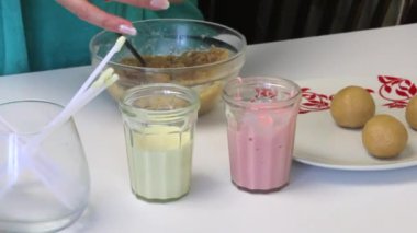 Masanın üzerine krema kek POP'lar için ve onlar için yemek çubukları ile gözlüğüm. Kadın bisküvi topları alır. Pasta çıkar için sırlı pişirme.