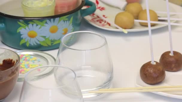 皿の上にあるポップ ケーキを作る付着箸でビスケット ボール テーブルの近くのアイシングでメガネは します — ストック動画