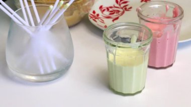 Masanın üzerine krema kek POP'lar için ve onlar için yemek çubukları ile gözlüğüm. Kadın bisküvi topları alır. Pasta çıkar için sırlı pişirme.