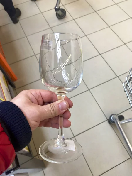 De man in de winkel nam een glazen beker in zijn hand. — Stockfoto